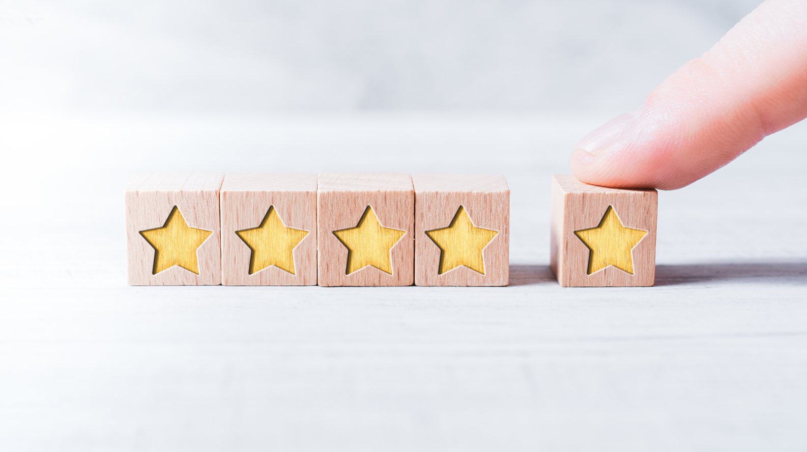 Five wooden blocks with yellow stars, meant to depict online reviews; social proof