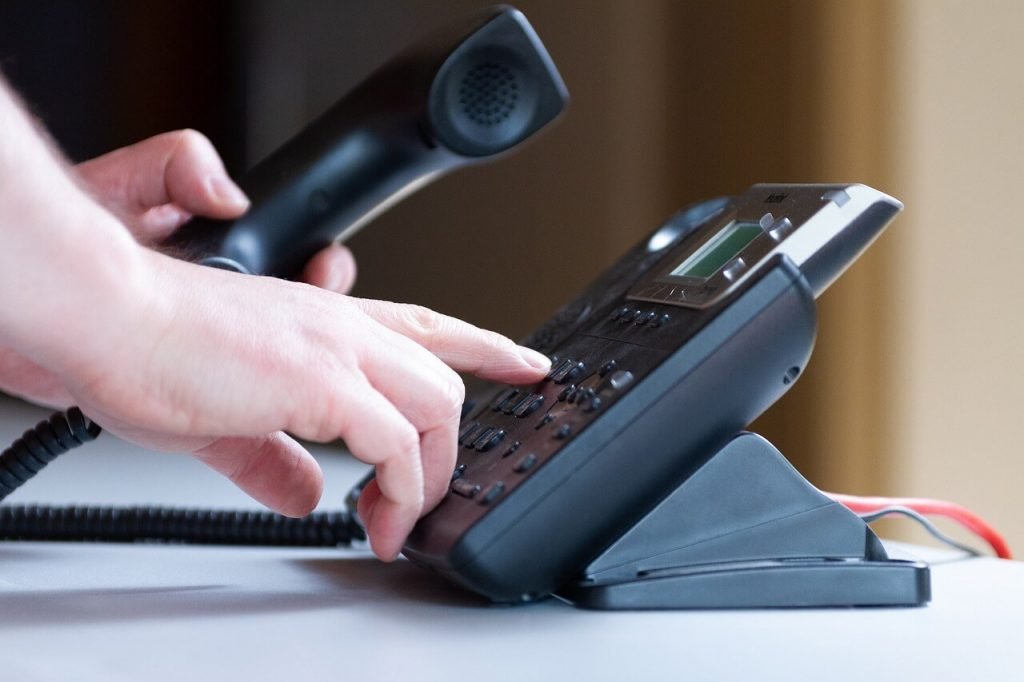 Male hand dialing an office phone.