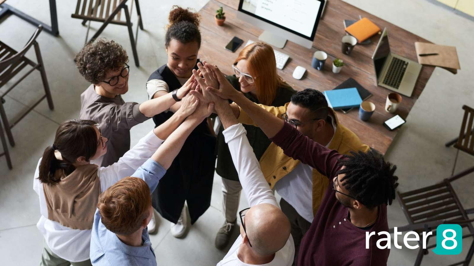 Multigenerational team putting hands in middle. rater8 logo in bottom right.