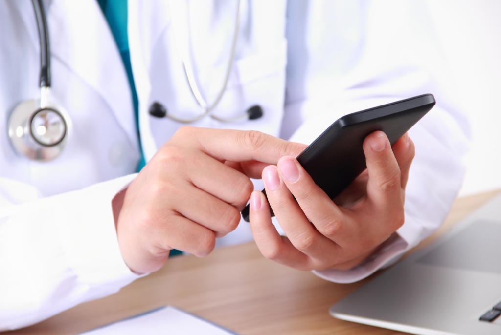 Doctor in white coat uses cell phone.