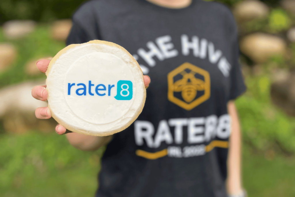 A rater8 employee holds a cookie with the rater8 logo on it; IRL 2022
